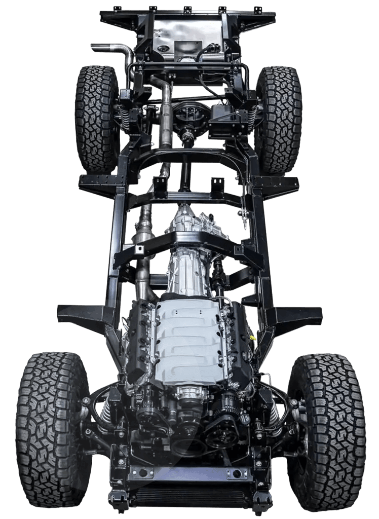 Overhead shot of a Defender chassis during the galvanization stage of a Monarch build, showing the bare frame being prepared for hot-dip coating