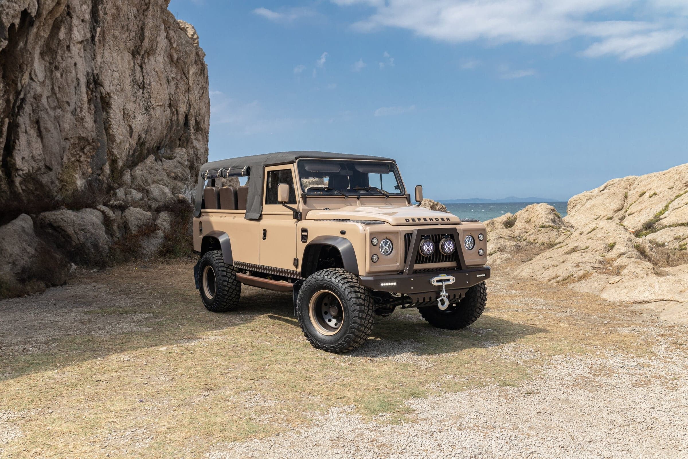 Completed bespoke Land Rover Defender 110 restomod with a custom exterior finish, parked on a gravel driveway.